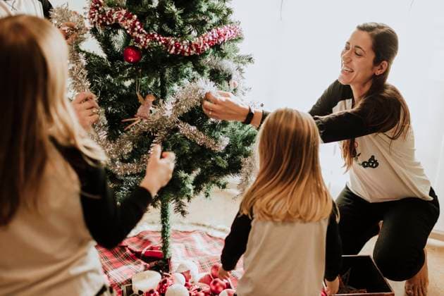 Cheerful parents with daughters decorating Christmas tree at home model released Symbolfoto property released GMLF00951