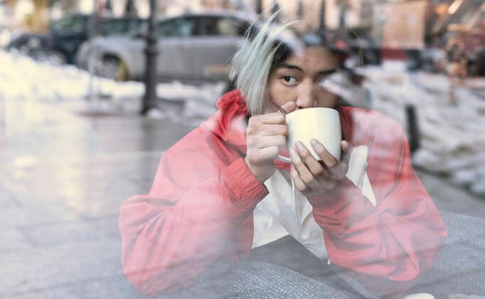 Asian man drinking coffee seen through glass in cafe during winter model released Symbolfoto JCCMF01139