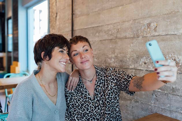 IMAGO Creative: Landleben - Essen Friends taking selfie on mobile phone while sitting at restaurant model released Symbolfoto property released JRVF00105