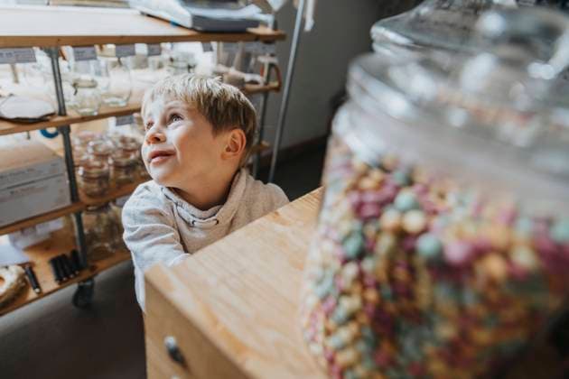 Blond little boy day dreaming while standing in candy store model released Symbolfoto property released MFF06901