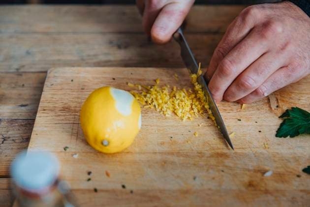 Close-up of chef cutting lemon peel on cutting board in kitchen model released Symbolfoto property released MFF06962
