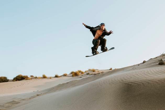 IMAGO Creative: Sport Dichotomien - Land und Wasser Young man performing stunt while standboarding at Almeria, Tabernas desert, Spain model released Symbolfoto MIMFF00437