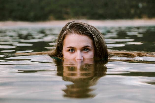 IMAGO Creative: Dichotomien, Reflexionen Young woman swimming in lake model released Symbolfoto MRRF00815