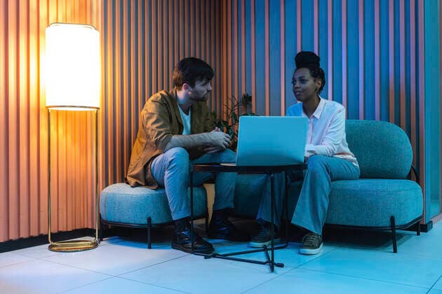 Male and female colleagues with laptop planning while sitting in illuminated work place model released Symbolfoto property released VPIF03430