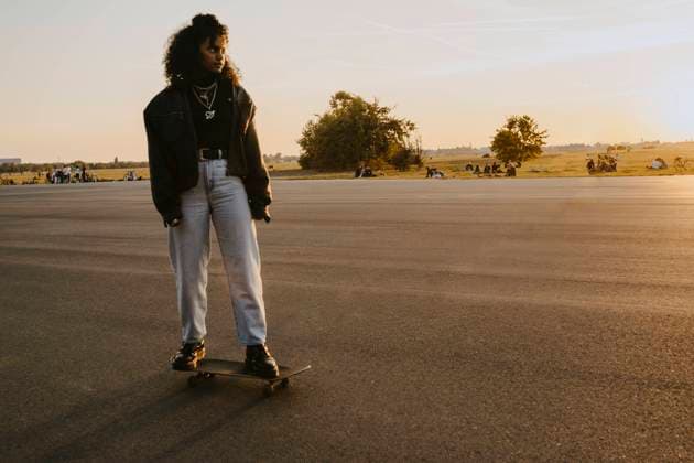 IMAGO Creative: Menschen in Berlin Woman looking away while standing on skateboard in park during sunset Germany, Berlin, model released Copyright: xMaskotx , MA84340