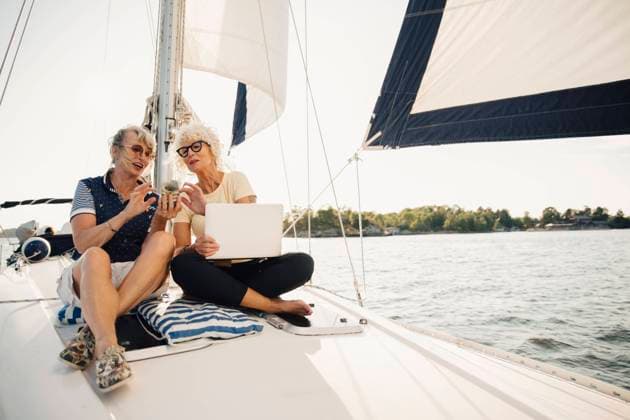 Internationaler Tag der Freundschaft IMAGO Creative, Internationaler Frauenmonat, Entrepreneurinnen Senior female friends using smart phone while sitting on boat during sunny day Sweden, Stockholm, model released, property released Copyright: xMaskotx , MA84581