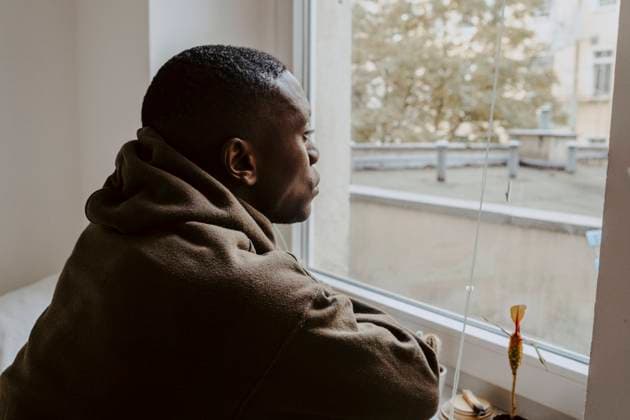 Thoughtful man looking through window at home Germany, Berlin, model released, property released Copyright: xMaskotx , MA84892