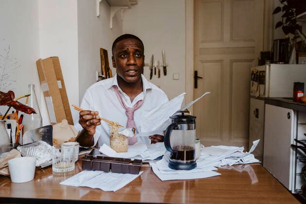 Thoughtful male entrepreneur with paper document having noodles at table in living room Germany, Berlin, model released, property released Copyright: xMaskotx , MA84917