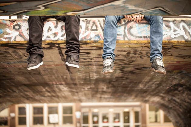 Two friends with legs hanging off concrete roof in skatepark Montreal, QC, Canada CR_CHPH210303C-621374-01 ,model released, Symbolfoto