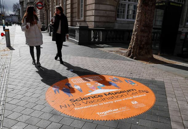 (210312) -- LONDON, March 12, 2021 -- Photo taken on March 11, 2021 shows people walking past a sign on the road outside the NHS COVID-19 Vaccination Centre in the Science Museum in London, Britain. Vaccination centres have opened at Westminster Abbey and Science Museum, according to NHS (National Health Service). ) BRITAIN-LONDON-COVID-19-VACCINATION CENTRES HanxYan 