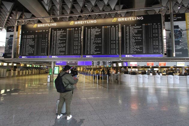 A traveler stands in front of the display board in Departure Hall B in the nearly deserted Terminal 1 at Frankfurt Airport, Hesse, Germany