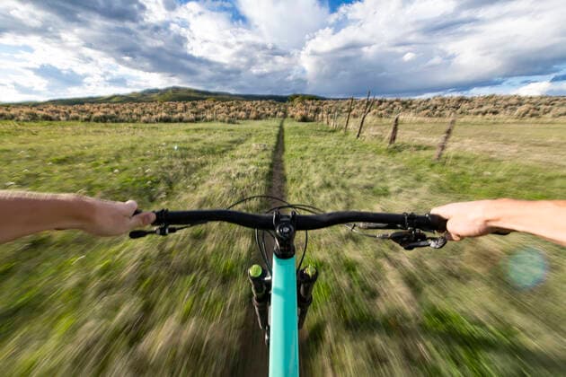 Cropped image of man riding bicycle on field Aspen, CO, United States CR_BRHU210312A-678770-01 ,model released, Symbolfoto