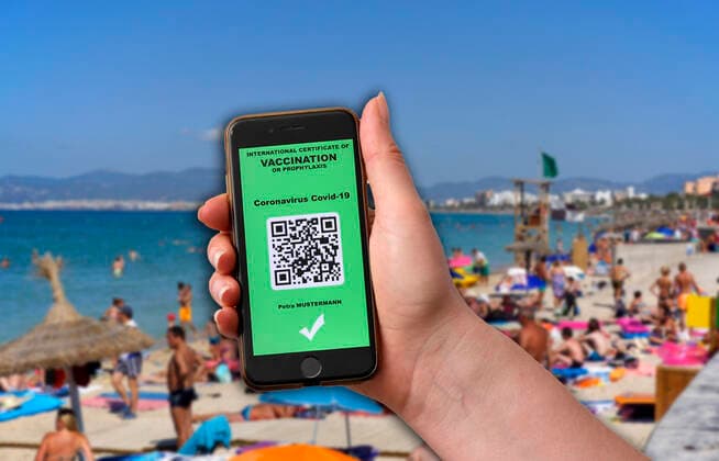 16 03 2021, symbol picture, picture montage vaccination A vaccination passport in digital form on the smartphone iPhone The vaccination passport would allow unrestricted travel again, symbol picture Mallorca Spain beach life El Arenal 16 03 2021, electronic vaccination passport for holiday travel 16 03 2021, electronic vaccination passport for holiday travel