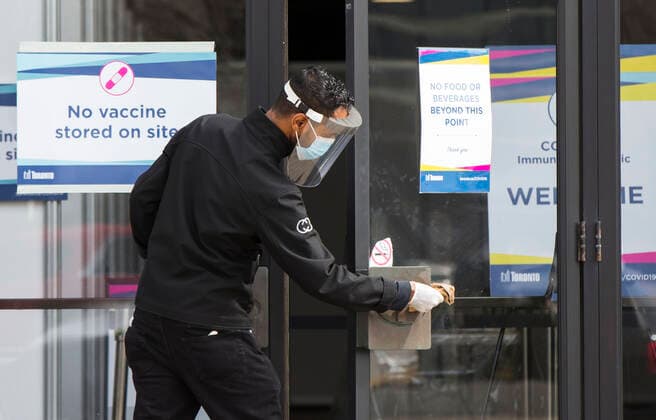 (210317) -- TORONTO, March 17, 2021 -- A staff member cleans door handles at the entrance of a COVID-19 immunization clinic in Toronto, Canada, on March 17, 2021. Starting Wednesday, the City of Toronto opened three City-operated COVID-19 vaccination clinics to vaccinate eligible residents born in 1941 or earlier who have confirmed appointments. (Photo by Xinhua) CANADA-TORONTO-COVID-19-IMMUNIZATION CLINICS FOR SENIORS-OPENING ZouxZheng 
