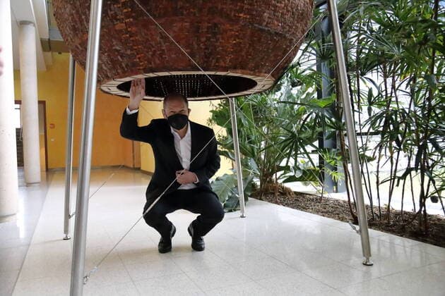 German Finance Minister and Chancellor candidate Olaf Scholz SPD learns about sustainable architecture and squats under a sphere made of pine bark by industrial designer Charlett Wenig during a visit to the Biomaterials Department of the Max Planck Institute of Colloids and Interfaces at the Potsdam Science Park in Potsdam Golm, 18 March