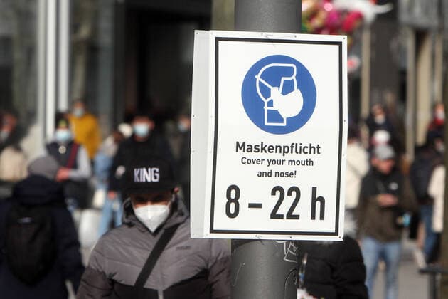 A sign with pictogram and inscription Mask obligation from 8 to 22 oclock hangs in the shopping street and pedestrian precinct Zeil in the city centre of Frankfurt, Hessen, Germany, which is strongly frequented by pedestrians.