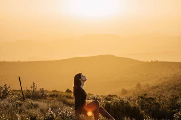 IMAGO Creative: Kulturelle Folgen der Pandemie: Gesundheitsbewu?tsein und Alleinsein Side view of peaceful female traveler sitting on hill with closed eyes and enjoying nature in highlands at sundown, Model released Copyright: xAdrianxVilanovax MR