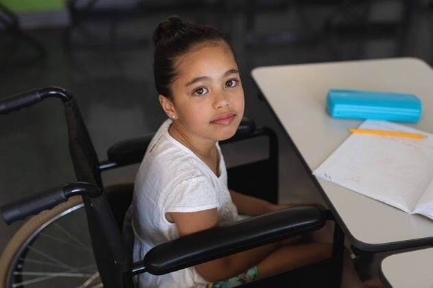 High angle view of disabled schoolgirl looking at camera and sitting at desk in classroom High angle view of disabled schoolgirl looking at camera and sitting at desk in classroom of elementary school, model released, , property released, capetown, 28.01.2019, 1227860.jpg, school, elementary school, classroom, desk, bench, casual clothing, notebook, pencil, pencil box, school kid, schoolgirl, student, classmate, sitting, looking, looking at camera, childhood, innocence, development, education, academic, information, knowledge, lifestyle, elementary, intelligent, intelligence, wisdom, wheelchair, disabled, handicapped, physical impairment Child, Girl, Female, Mixed-Race, 8-9 Years, Girls, Mixed-Race Person Indoors,Day