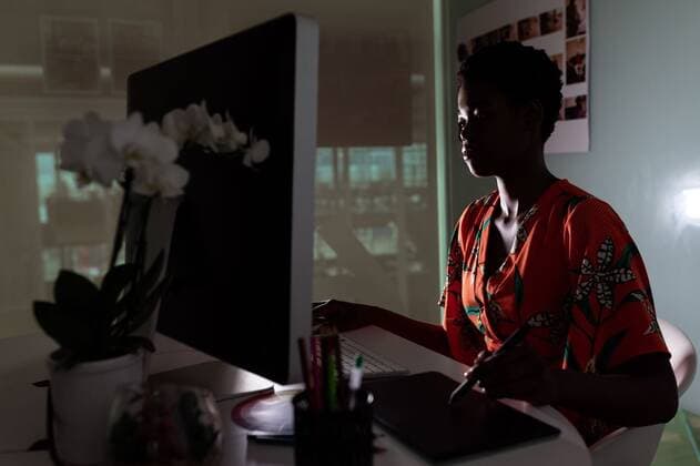 Female Graphic designer using graphic tablet at desk Side view of young pretty African-American female graphic designer using graphic tablet at desk in office. This is a casual creative start-up business office for a diverse team, model released, , property released, Cape Town, South Africa, 17.03.2019, 1266720.jpg, gen z, generation z, graphic designer, artist, business, businesswoman, executive, associate, occupation, profession, professional, skill, expertise, creative, entrepreneur, corporate, company, office, workplace, desk, color swatch, colored pencil, pen holder, dark, sitting, working, editing, graphic tablet, digitizer, graphic, stylus, digital tablet, wireless technology, computer, desktop pc, electronic, personal computer, key