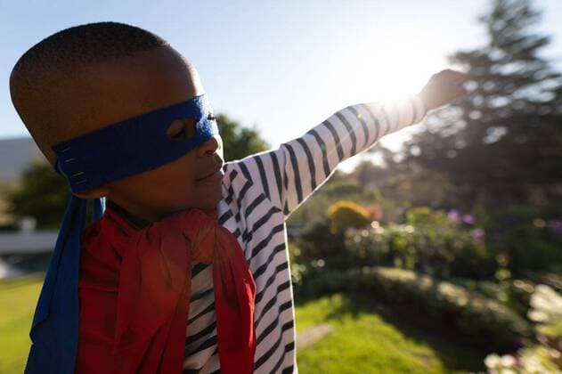 IMAGO Creative: NGO, Ausbildung für Kinder Superhero boy in garden Side view of a young african american boy dressed in a superhero costume with a red cape and a blue mask in a garden, smiling with an arm outstretched, model released, , property released, Cape Town, South Africa, 06.09.2019, 1289335.jpg, domestic life,home,childhood,leisure,freedom,spare time,free time,play,playing,mask,cape,red,blue,superhero,fun,costume,dressing up,garden,creative,fantasy,imagination,individuality,carefree,creativity,expression,content,happy,smiling,arm,outstretched,sunlight,sunshine,summer,lifestyle,active,activity,pleasure,joy,enjoying,alone,sky Child,Boy,Male,Black Outdoors,Side view,Close-up,Copy space,Day,Head and shoulders