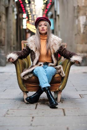 Woman with fur jacket sitting on armchair at alley model released Symbolfoto AGOF00082