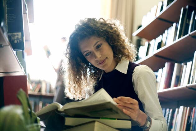 Young woman reading books at library model released Symbolfoto property released AJOF01052