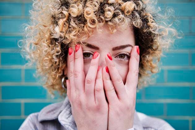 Curly haired woman hiding face with hands model released Symbolfoto ASGF00075