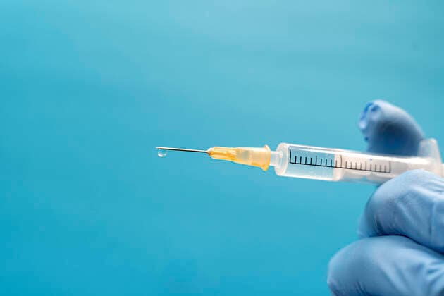 Hand of person wearing protective glove holding single syringe model released Symbolfoto DRF01767