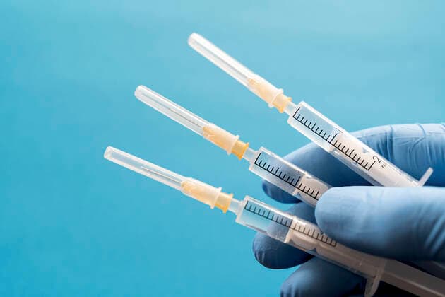 Hand of person wearing protective glove holding three syringes model released Symbolfoto DRF01768
