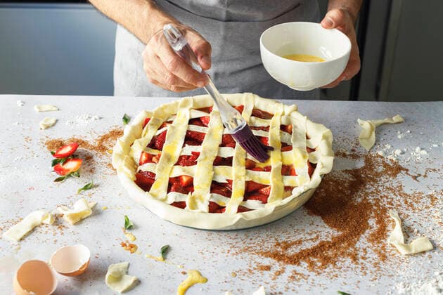 Hands of man applying egg wash to raw strawberry pie model released Symbolfoto property released IFRF00457