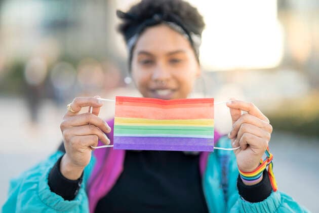 Young woman holding rainbow LGBTQIA mask in city during protest model released Symbolfoto JCCMF01334