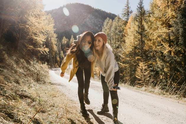 Playful friends laughing while standing together in forest model released Symbolfoto LHPF01397