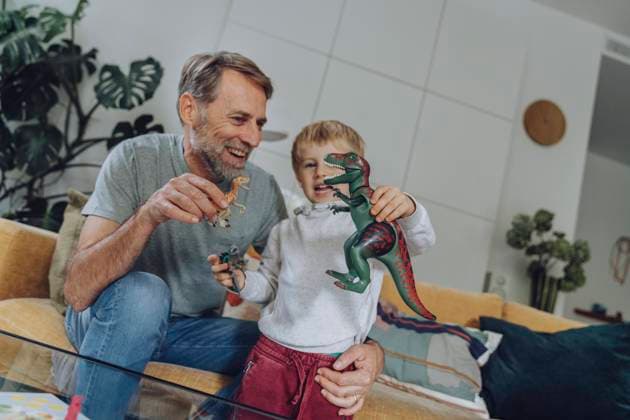 Father and son playing with dinosaur toy in living room model released Symbolfoto property released MFF07151
