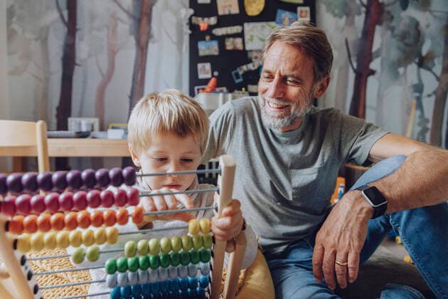 Happy father watching son counting abacus in bedroom model released Symbolfoto property released MFF07174