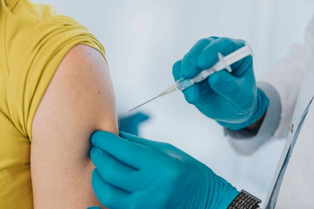 Doctor giving COVID-19 vaccine on patient hand at examination room model released Symbolfoto property released MFF07401
