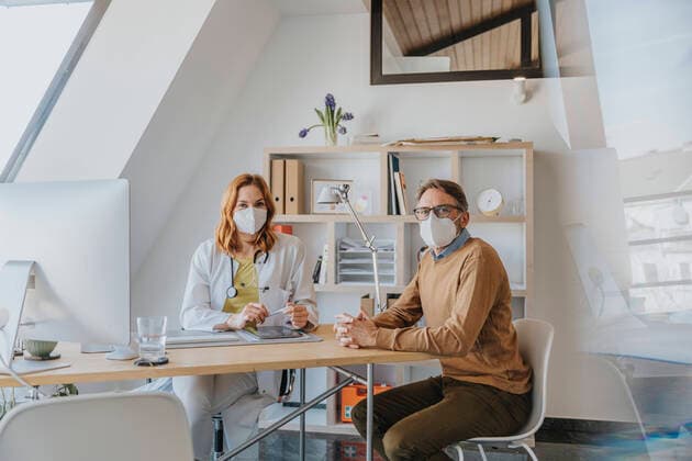 IMAGO Creative: Lokalhelden - Gesundheits- und Rettungskräfte Healthcare worker and patient with protective face mask sitting at doctor s office model released Symbolfoto property released MFF07559