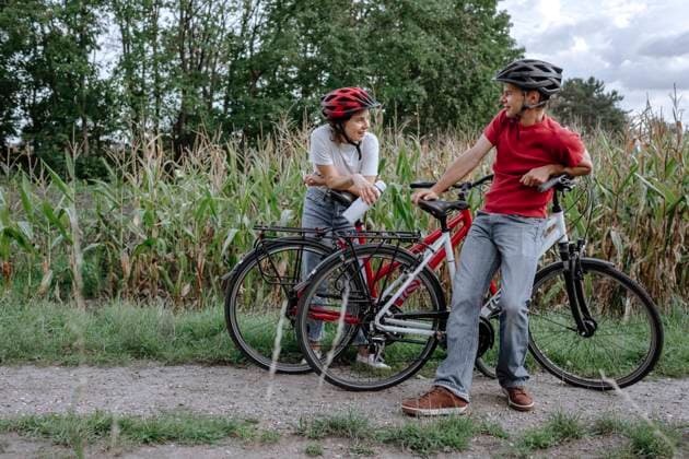 Father and daughter talking while leaning on bicycle at agricultural field model released Symbolfoto OGF00919