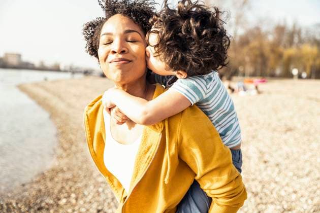 Boy kissing while piggybacked by mother on sunny day model released Symbolfoto UUF23024