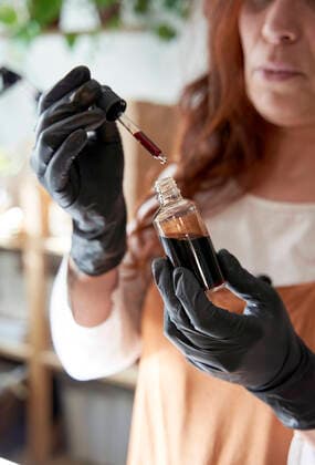 Mature female influencer holding oil bottle at workshop model released Symbolfoto property released VEGF03979