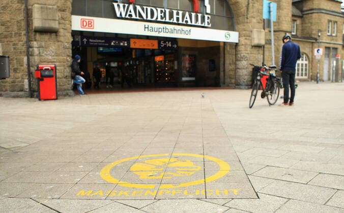 A notice is sprayed on the paving stones in front of the entrance to the main station that masks are compulsory here St Georg Hamburg
