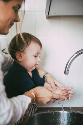 Mother helping baby girl washing hands under sink in kitchen Sweden, Stockholm, model released, property released Copyright: xMaskotx , MA85677
