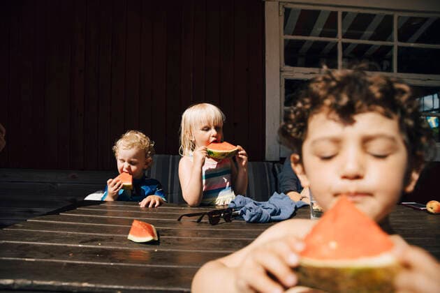 Siblings eating fruit while standing by table during sunny day Sweden, Tierp, model released, property released Copyright: xMaskotx , MA85511