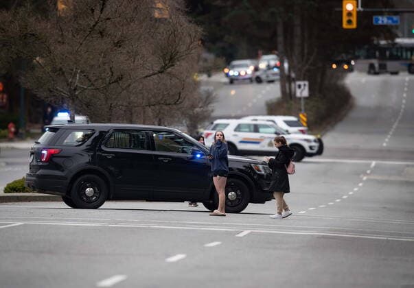 March 27, 2021, North Vancouver, BC, Canada: People stand near an RCMP vehicle blocking the road not far from the Lynn Valley Library, in North Vancouver, B.C., Saturday, March 27, 2021. Police say multiple victims were stabbed inside and outside the library today. North Vancouver Canada  - ZUMAc35_ 20210327_zaf_c35_044 Copyright: xDarrylxDyckx
