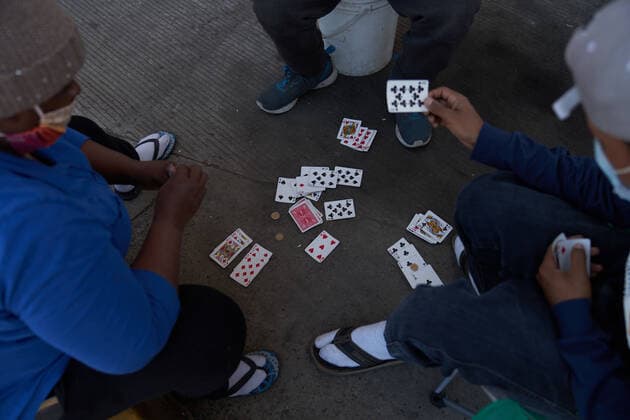 March 28, 2021, Tijuana, Mexico: Migrants play cards on the street to pass time. Migrants from Central America are stuck living in tents on the street in Tijuana, Mexico on the border while they wait for President Joe Biden to open the American border. Tijuana Mexico - ZUMAd211 20210328_zap_d211_019 Copyright: xAllisonxDinnerx