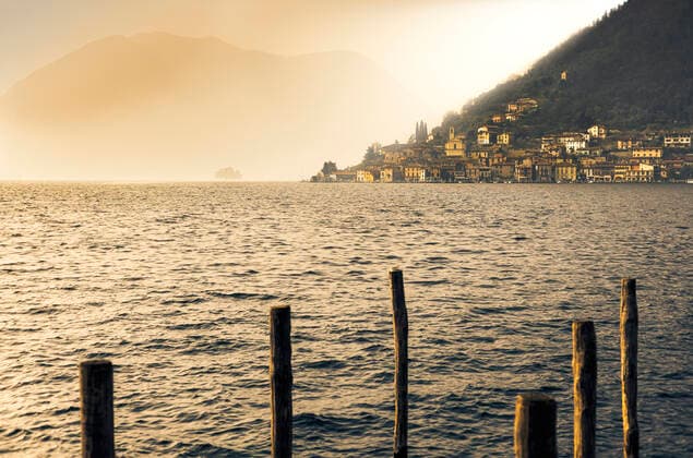 Light in the fog illuminates Peschiera Maraglio village, Monte Isola, Lake Iseo, Brescia province, Lombardy, Italian Lakes, Italy, Europe Copyright: FrancescoxBergamaschi 1269-694