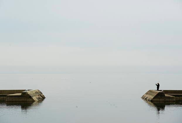 April 5, 2021, Toronto, on, Canada: A man takes a photograph over looking a calm Lake Ontario near Humber Bay during the COVID-19 pandemic in Toronto on Monday, April 5, 2021. Toronto Canada  - ZUMAc35_ 20210405_zaf_c35_035 Copyright: xNathanxDenettex