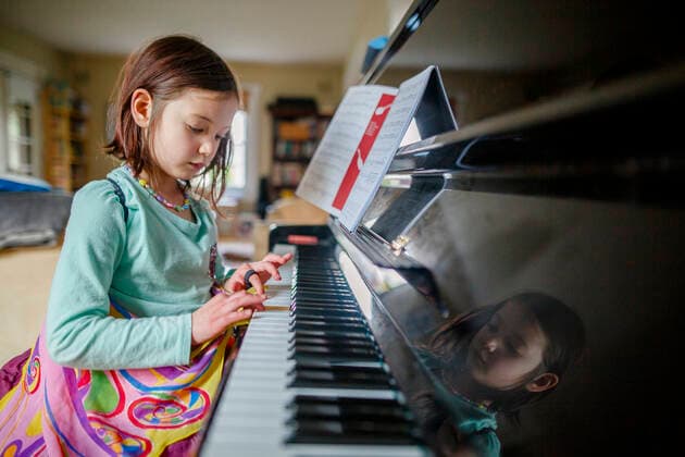 A little girl in butterfly wings sits at piano playing music indoors Columbus, OH, United States CR_RETI210406-662169-01 ,model released, Symbolfoto