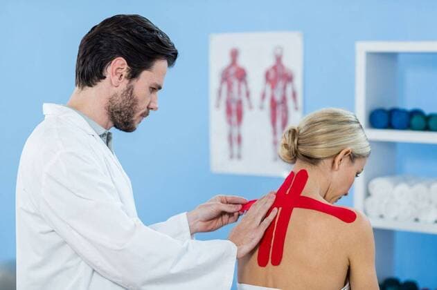 Physiotherapist sticking tape on female patient Physiotherapist sticking tape on female patient in clinic, model released, Cape Town, South Africa, 01.06.2016, 804209.jpg, physio, physiotherapy, physiotherapist, orthopedic, physical therapy, therapy, physical therapist, doctor, clinic, hospital, specialist, profession, professional, lab coat, patient, sticking, assisting, kinesiotape, kinesiotaping, sick, illness, medical, assistance, treatment, care, cure, recovery, health, health service, bodycare, healthcare, healthcare and medicine, expertise 20s, Young Adult, Man, Male, Caucasian, 30s, Mid Adult, Woman, Female, 25-29 Years, Young Men, Caucasian Ethnicity, 30-34 Years, Mid Adult Women Indoors