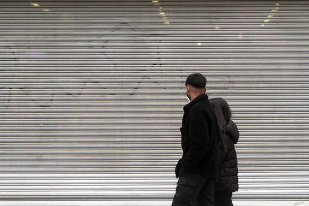 Passers-by walk by a shop closed with a roller shutter in the shopping street pedestrian zone Zeil in downtown Frankfurt, Hesse, Germany