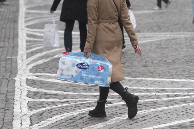 Woman walks with a large pack of toilet paper in downtown Frankfurt, Hesse, Germany